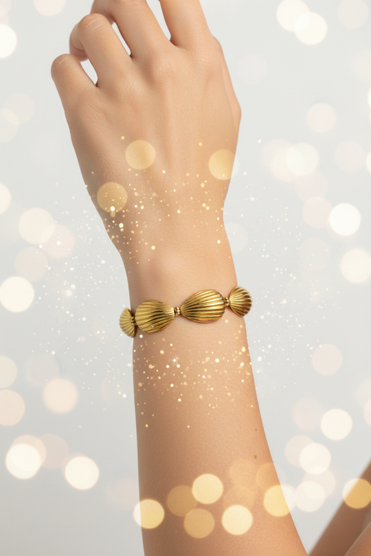 Arm met gouden schelpen armband en sparkles