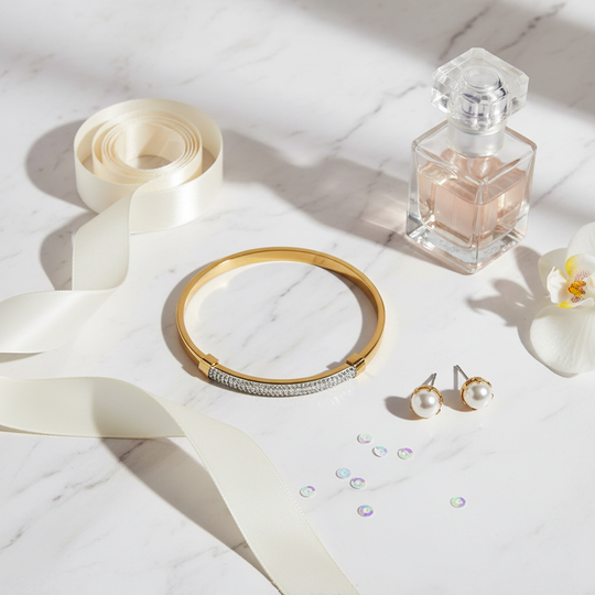 Gouden bangle armband flat lay met satijn en parfum