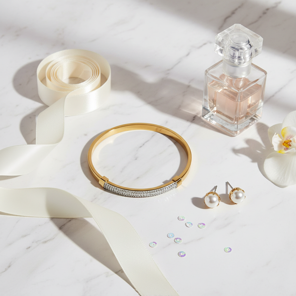 Gouden bangle armband flat lay met satijn en parfum