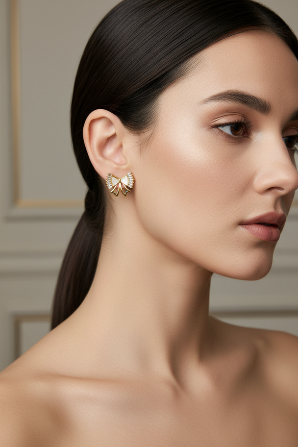 Model draagt gouden strik oorknopjes met kristallen