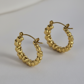 Detail shot gouden creool oorbellen met hartjes