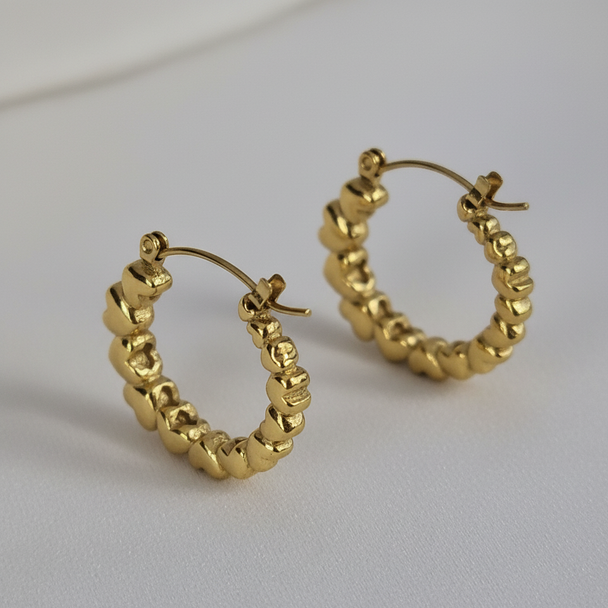 Detail shot gouden creool oorbellen met hartjes