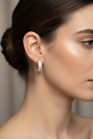 Model draagt gouden creool oorbellen met baguette zirkonia