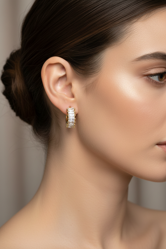 Model draagt gouden creool oorbellen met baguette zirkonia