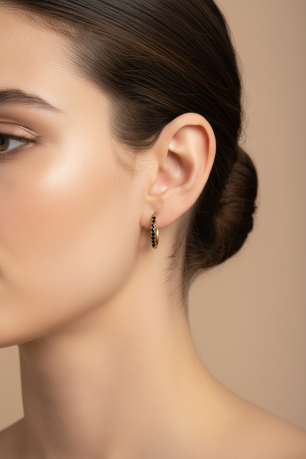 Model draagt gouden creool oorbellen met zwarte zirkonia