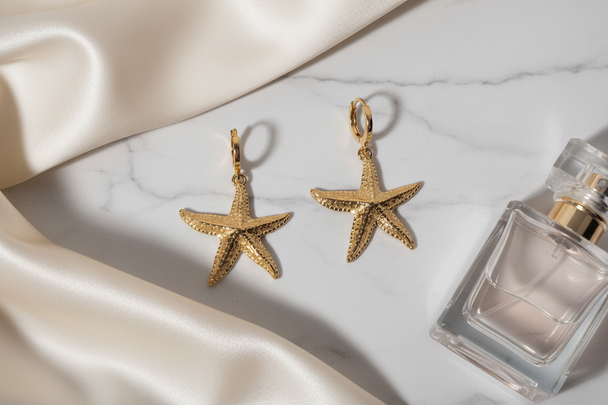 Gouden zeester creool oorbellen op wit marmer met satijn en parfum - paar