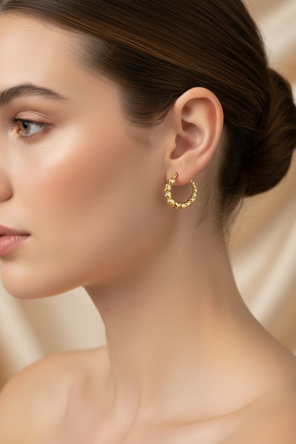 Model draagt gouden creool oorbellen met hartjes