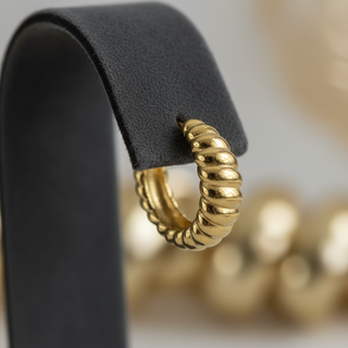 Detail shot gouden croissant creool oorbellen gedraaid