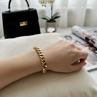 Gouden schakelarmband gedragen door model met luxe accessoires