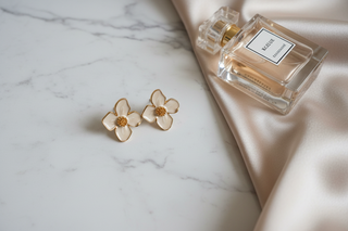 Bloem oorknopjes beige goud op wit marmer met satijn en parfum