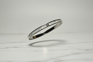 Zilver armband zwevend op wit marmer